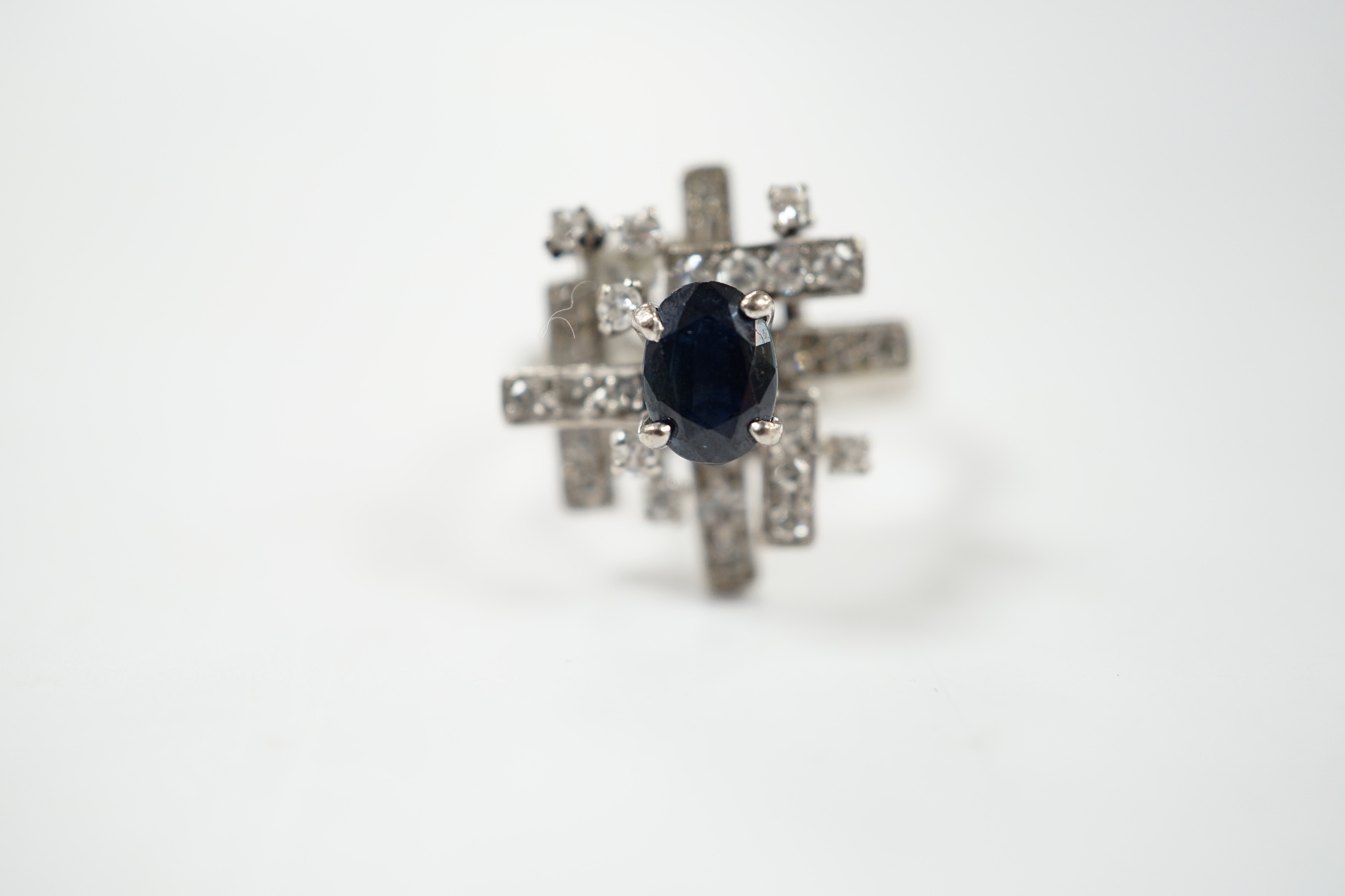 A modern 18k white metal, sapphire and diamond set modernist ring, size K/L, gross weight 6.1 grams.